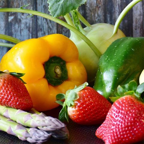 Collection of fruits and vegetables on a table, including asparagus, peppers, and strawberries
