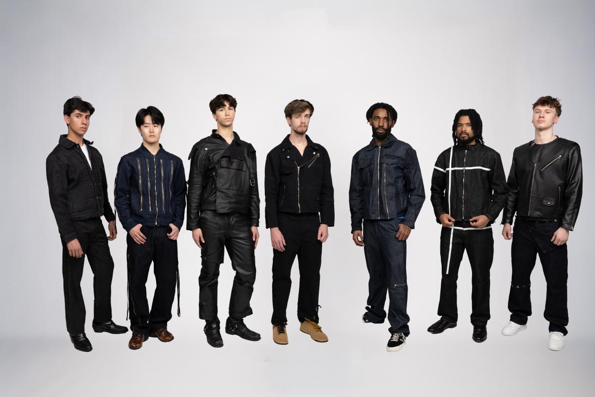 several models wear black and blue trousers and jackets with unique designs incorporating zippers