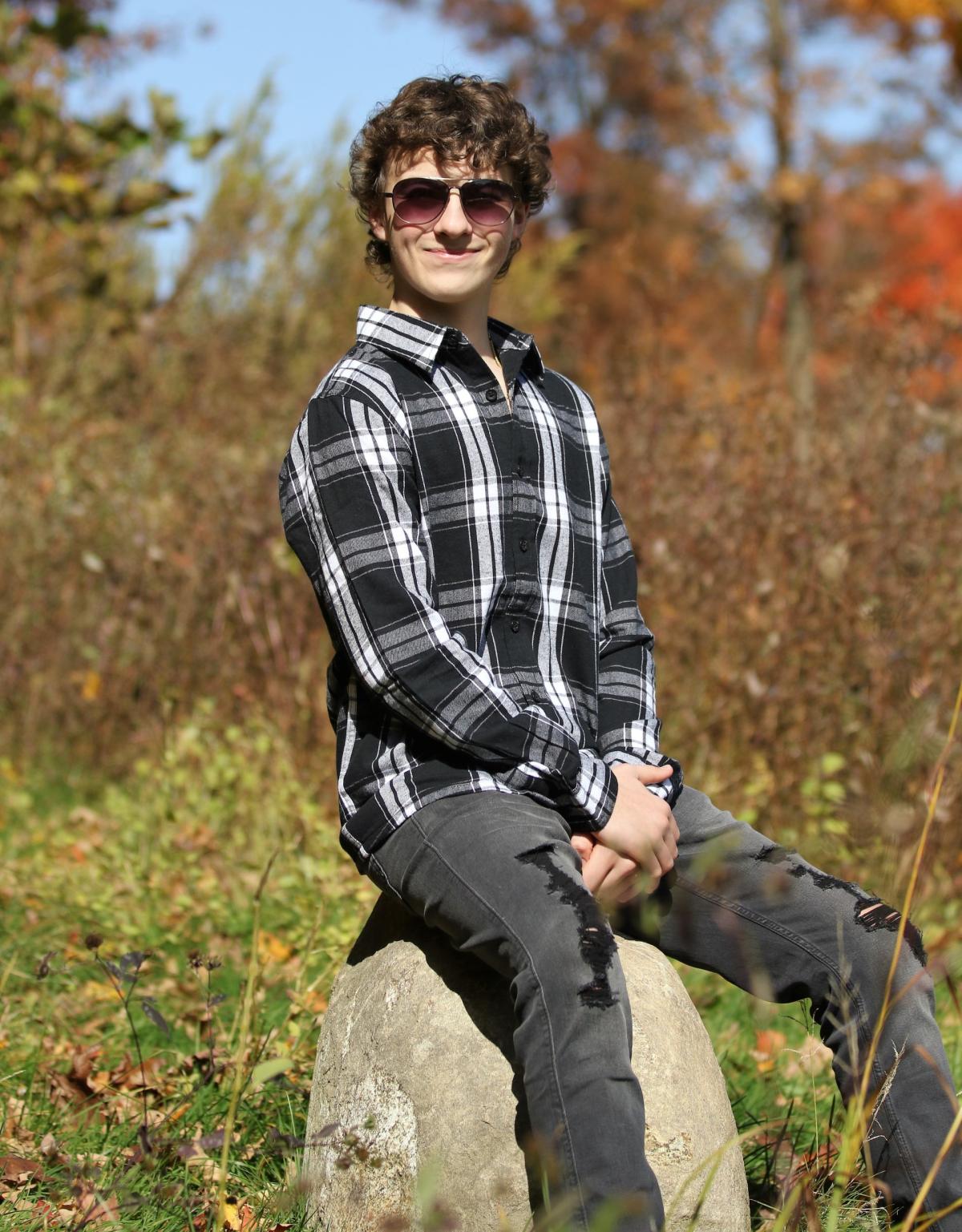 Honors College Student Phoenix Allen sits on a rock outside.
