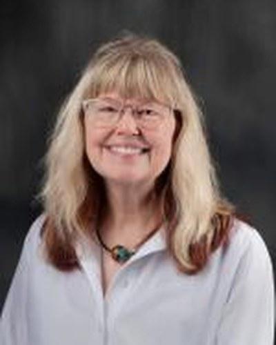 Professional portrait of a woman looking toward the camera against a solid backdrop.