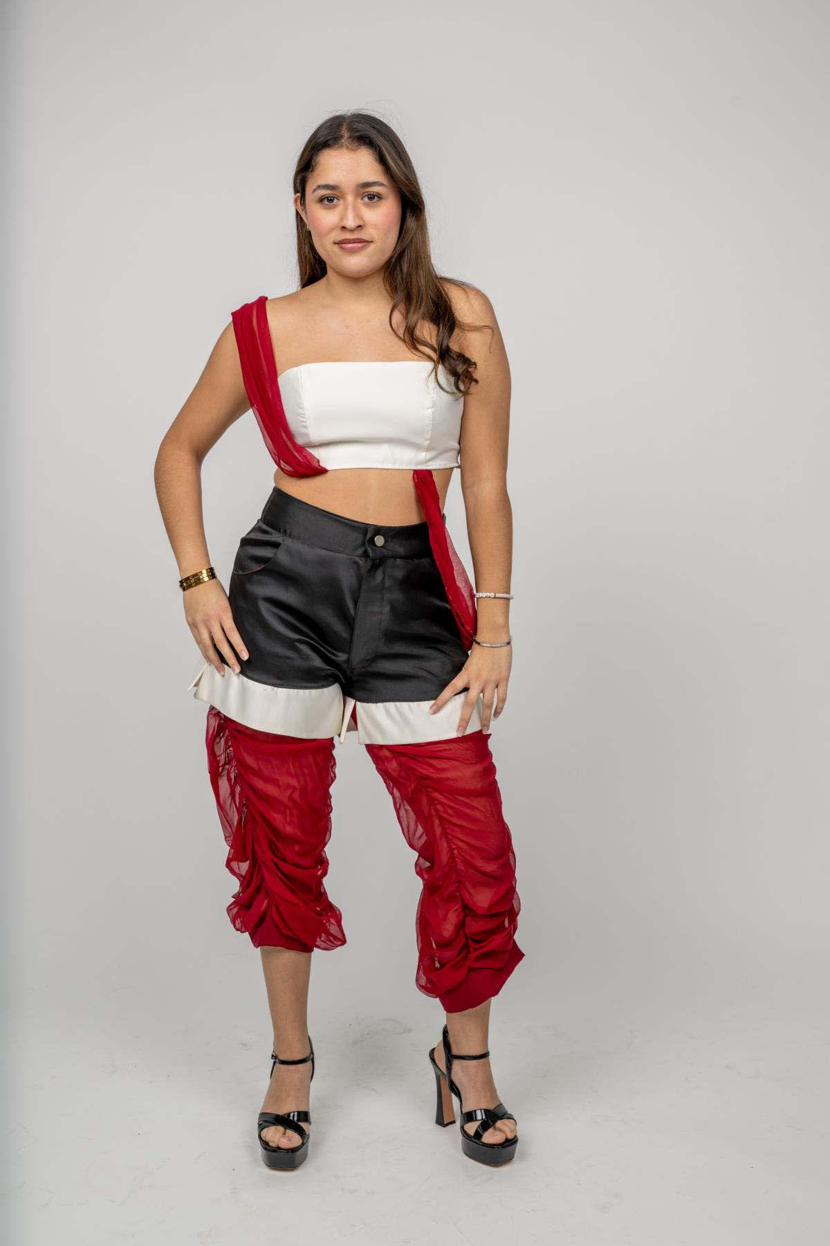a model wears a white tank top with red straps and black silk shorts over top ruffled tulle leggings