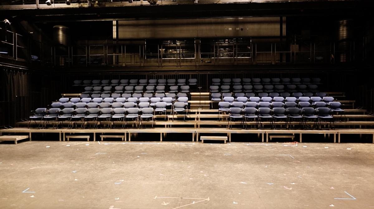 Blue auditorium seats lead down to an open stage