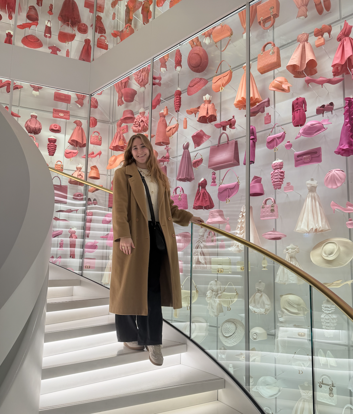 Lauren in a modern building with a colorful exhibit of accessories and dresses. 