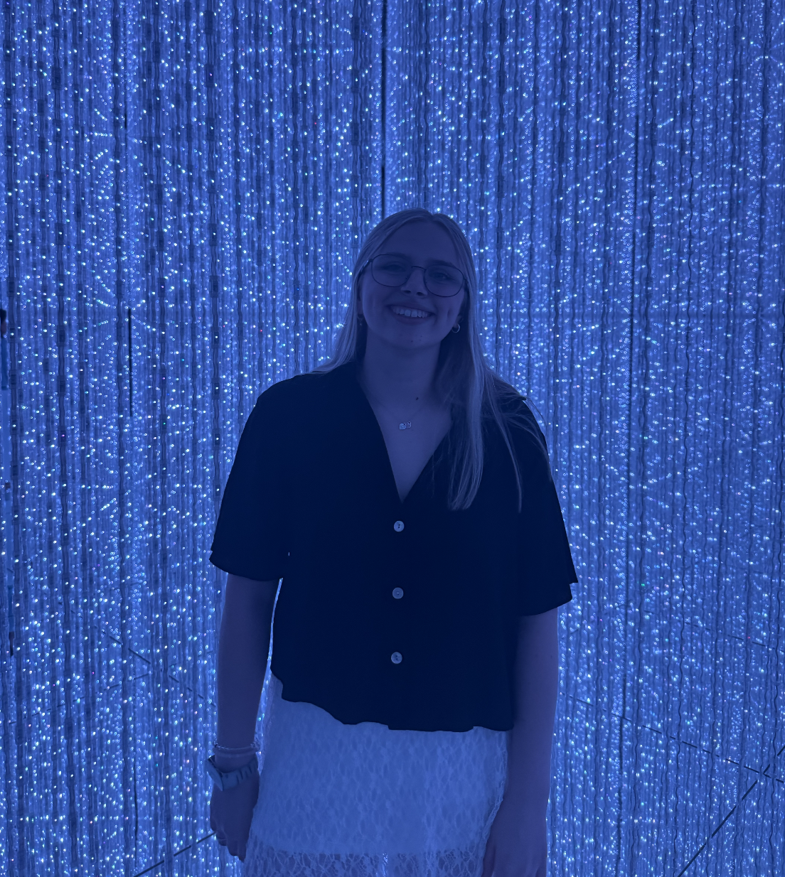Ashley at an immersive art exhibit with blue strings of light around her