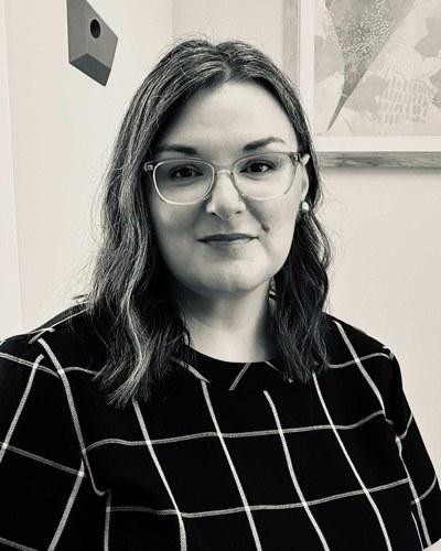 Professional headshot of a woman in business-casual attire against a neutral background.