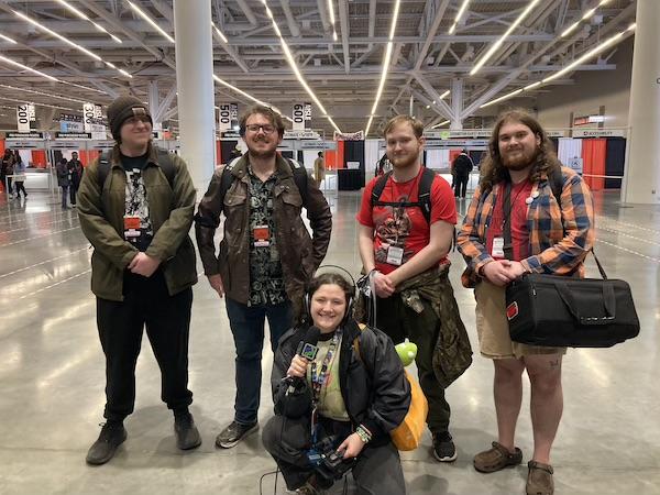 Five students standing in exhibit hall with video cameras and gear
