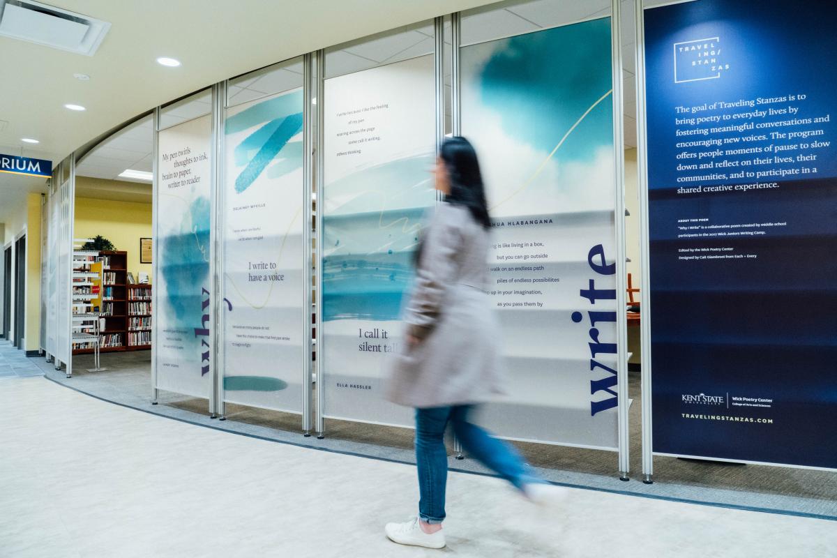 A person walks past the Wick Poetry Corner, with a poem mural in the background.