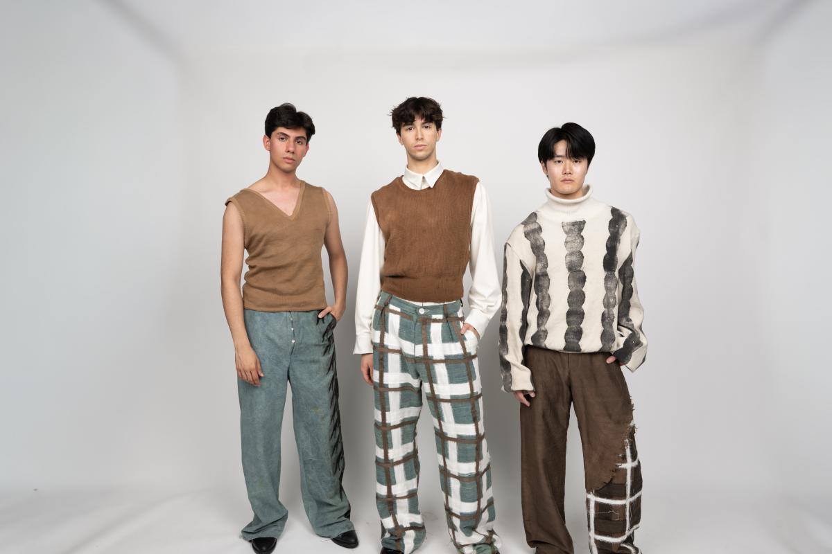 three models wear pants and sweaters featuring hand printed grid and circular patterns