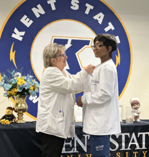 Alice Colwell, senior lecturer, pins the Arnold P. Gold Foundation "Keeping Healthcare Human}" lapel on BSN student, Emari Edmonds.