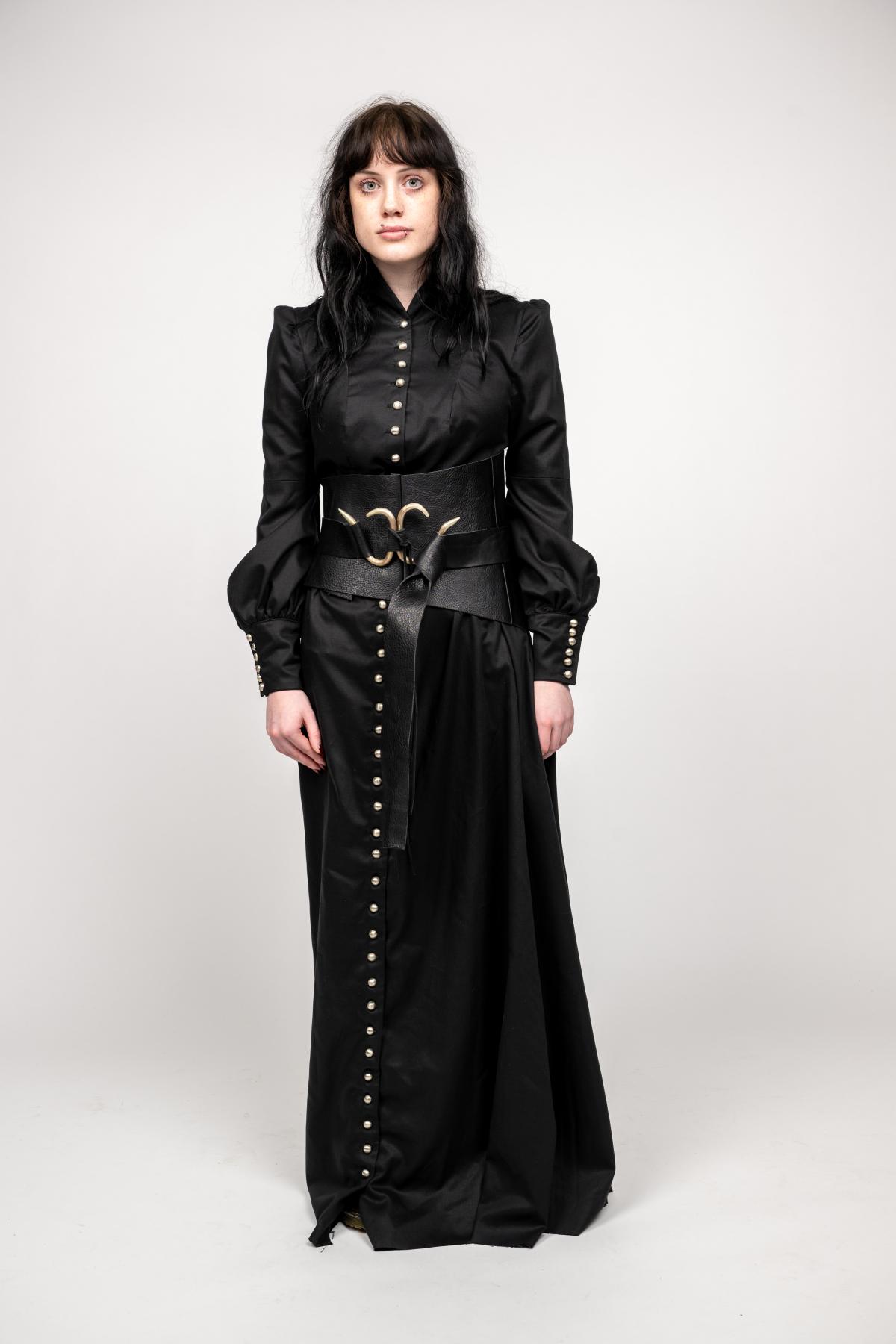 a model wears a long-sleeve black gown with buttons from the neck to the hem