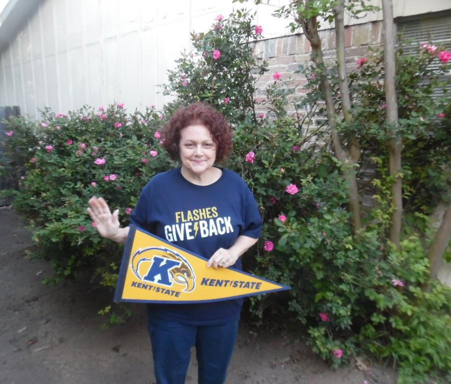 Alumni wearing Flashes Give Back t-shirt, holding Kent State pennant flag