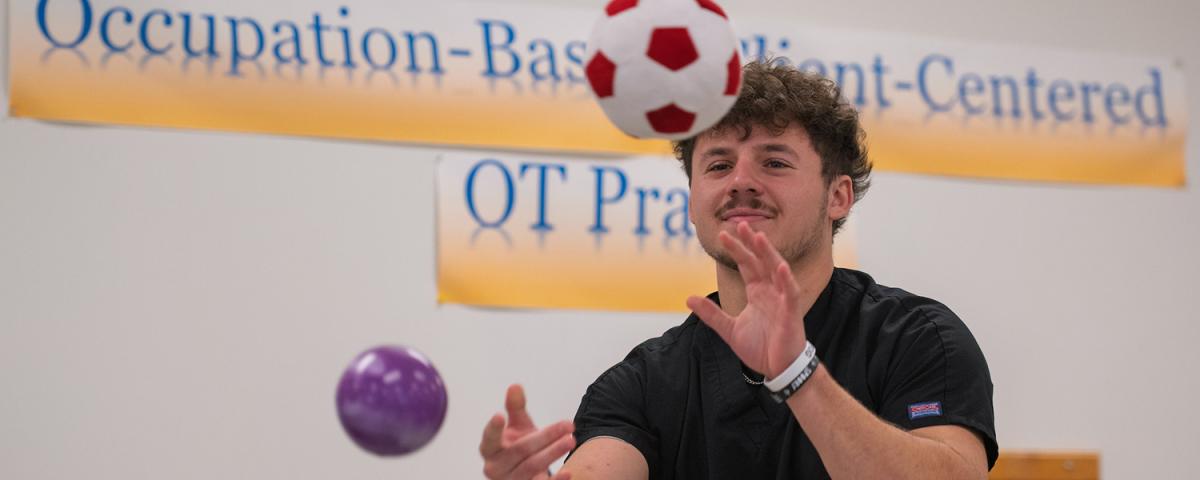 Male OTA student catches a red and white mini soccer ball