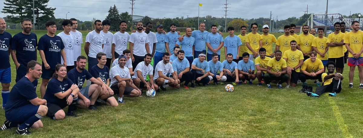 A large group of international scholars gathered in different colored t-shirts to play soccer (fútbol).