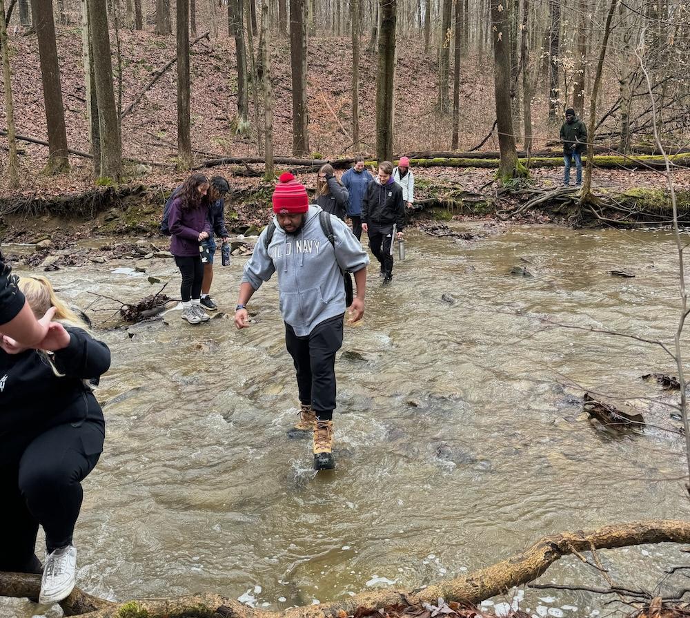 students hiking through water in field experience class