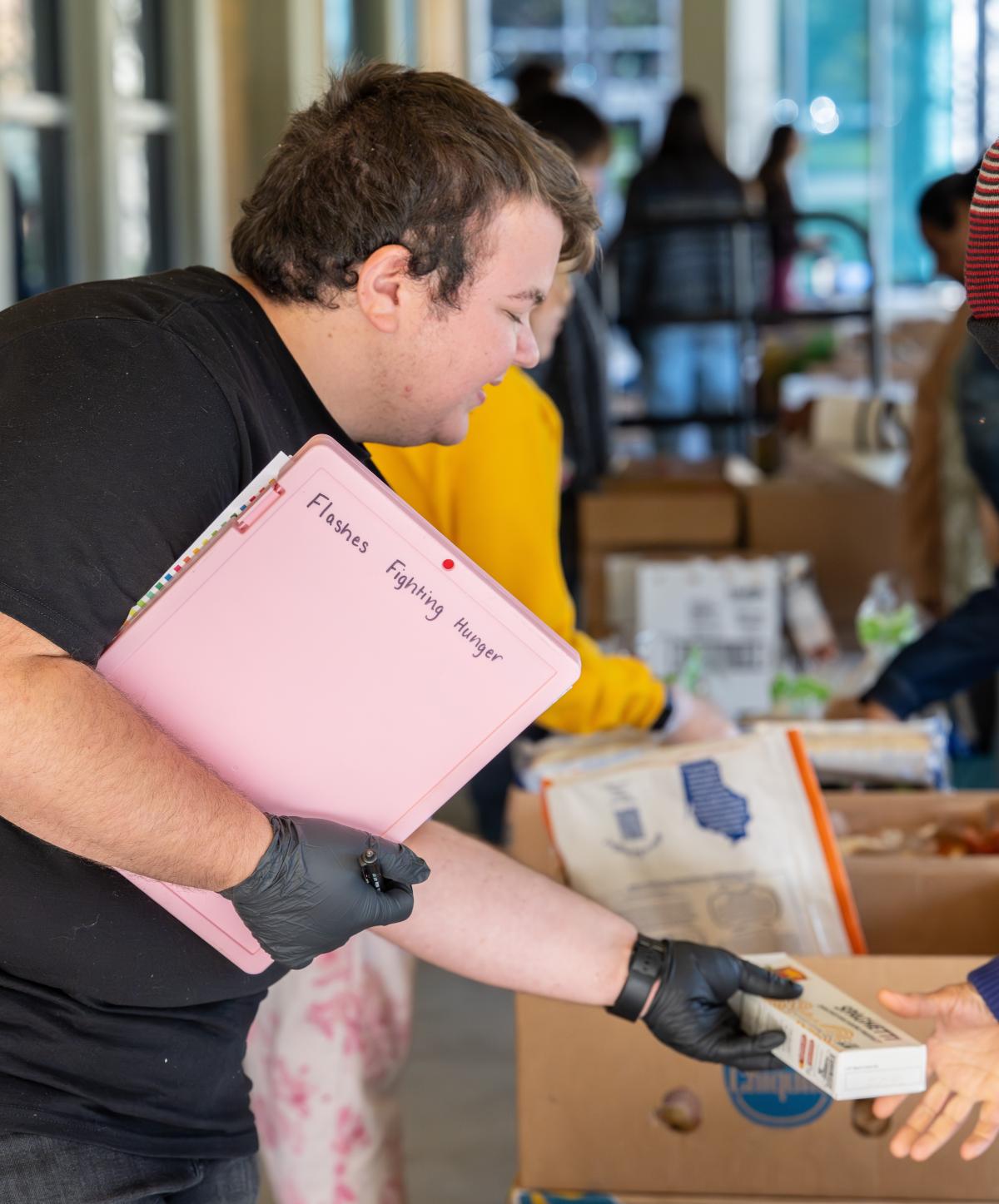 Food pantry worker passing box of pasta to client