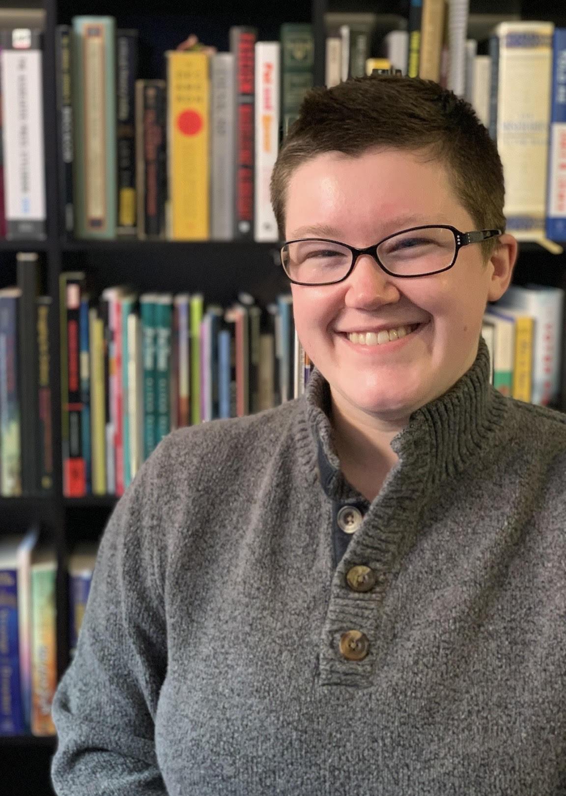 Moira Armstrong smiling in front of a bookshelf 