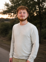 Portrait of CAE Student Jonny Burkhart outside wearing a white long-sleeved shirt. 