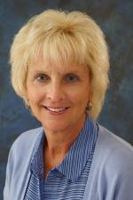 headshot for Tracey Motter with a gray background and blue blouse