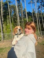 Photo of Taylor Smith holding a small beagle dog on her shoulder, smiling. 