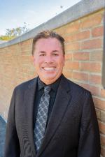Outside headshot of Timothy Cox in front of a brick wall