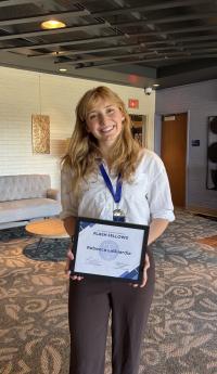 Rebecca LaGuardia standing for a photo while holding a Flash Fellow certificate. 