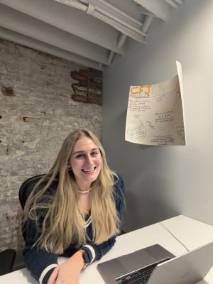 Alumna sitting at a desk with a laptop in front of her