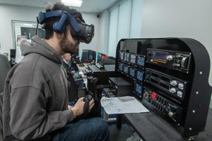 A student wears augmented reality glasses at a flight simulation in the XR Lab