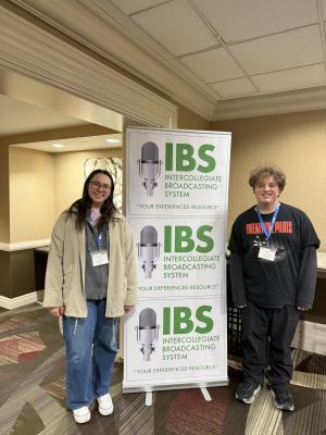 Kristina Hess and Fisher Brashear stand next to a display from IBS conference