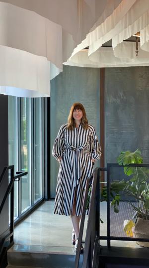 Kelly Velikonya Patel smiles beside a glass window