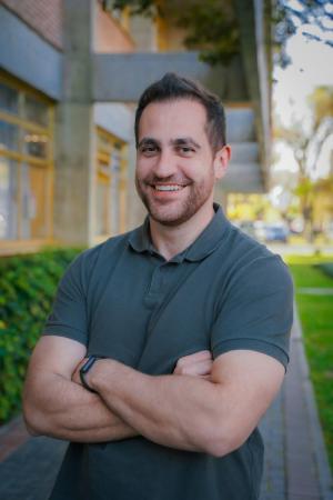 Murilo Karasinski standing with his arms crossed in front of a building