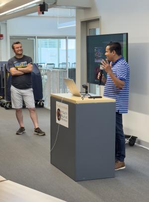 Two men at a podium and in front of a monitor