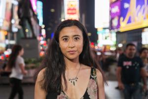 Portrait of Saya Woolfalk; woman with long dark hair with city lights in the background