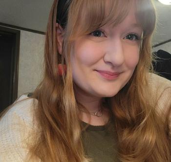 A young woman with strawberry blonde hair smiling at the camera