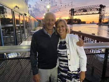 two people pose for a photo during the sunset over a lake