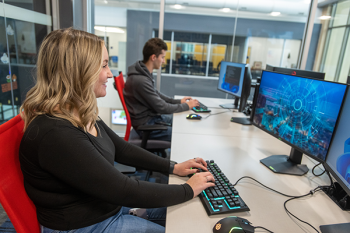 A young woman with blonde hair using a computer displaying a blue homescreen.