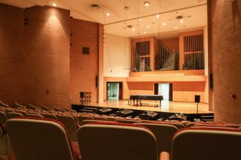 Empty seats leading up to a stage with covered piano