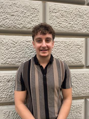 Paul poses in front of a stone wall