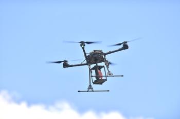 A quadcopter drone carries a football in a custom cradle device