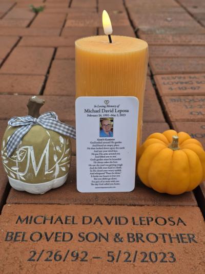 Candle in front of memorial brick for Michael Leposa with a prayer for him