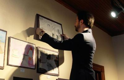 David Jones hangs a piece of art on the wall of the Conneaut Arts Center