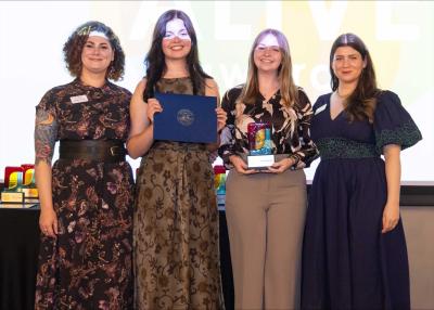 Two students accepting an award, event staff on both sides