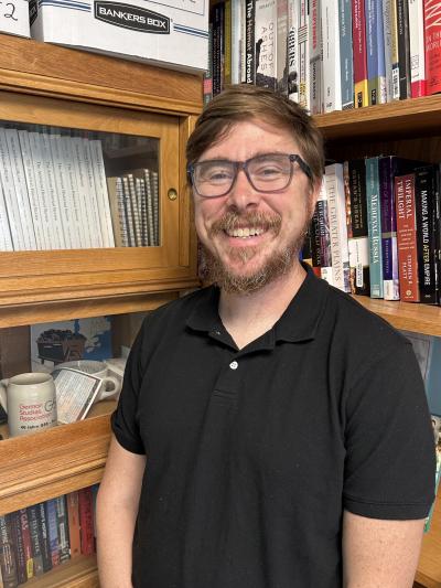 picture of Nick Ostrum standing in front of two book shelves