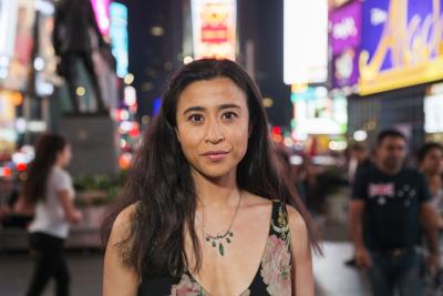 Portrait of Saya Woolfalk; woman with long dark hair with city lights in the background