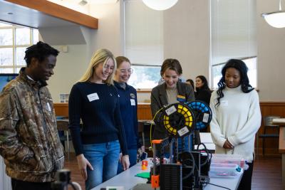 Event attendees gather around a 3D printer during an event for the Research Center for Educational Technology.