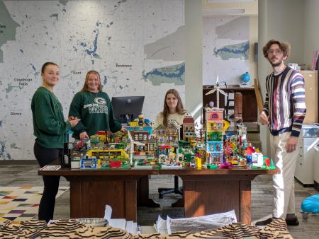 Students surround desk with maps and books