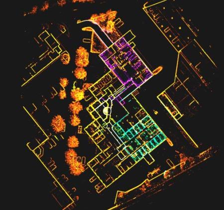 Overhead visualization of a building interior created from sensor data, showing walls, rooms, and objects outlined in color, with trees and exterior features visible around the structure.