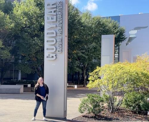 A woman standing next to a sign that says Goodyear World Headquarters