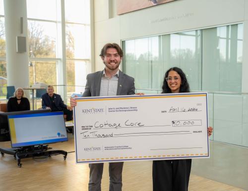 First place winners holding big check and smiling in Crawford Hall atrium with judges in background.