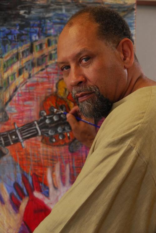 Curlee Raven Holton standing at and easel painting.