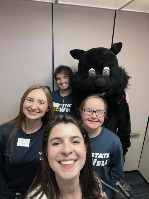 Kellyn (second row, right) posing with SRWC coworkers and a black squirrel mascot.